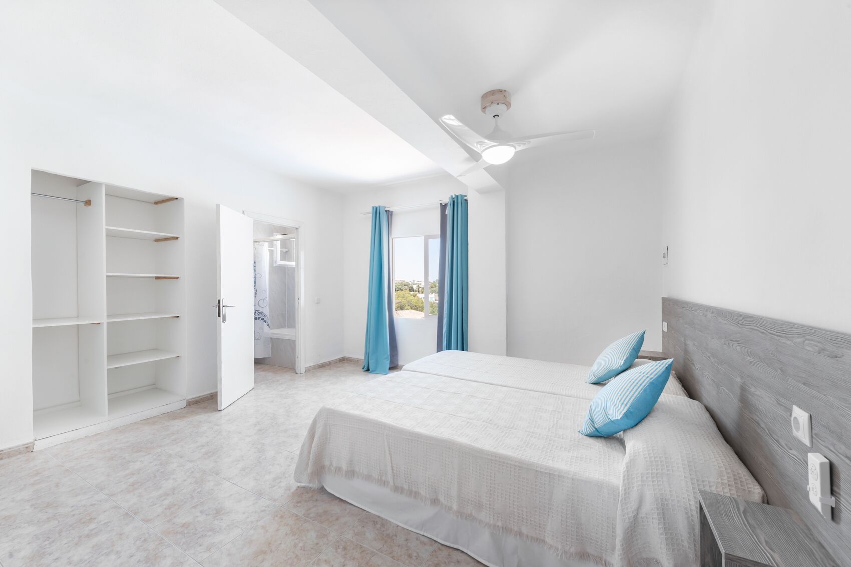 A bedroom with a bed, a wardrobe, and a ceiling fan.