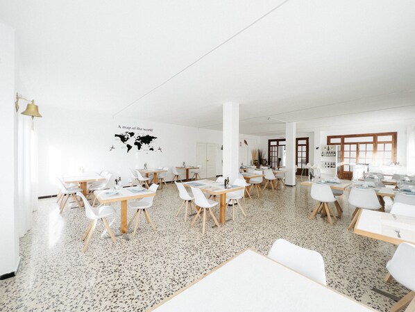A spacious room with white walls, a world map, and multiple tables and chairs.