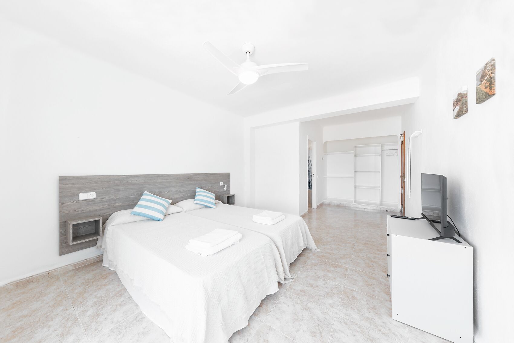 Un dormitorio moderno con cama, mesitas de noche, televisor y armario.