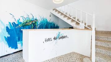 Un comptoir d’accueil orné d’un grand tableau représentant une tortue et un escalier menant à un étage supérieur.