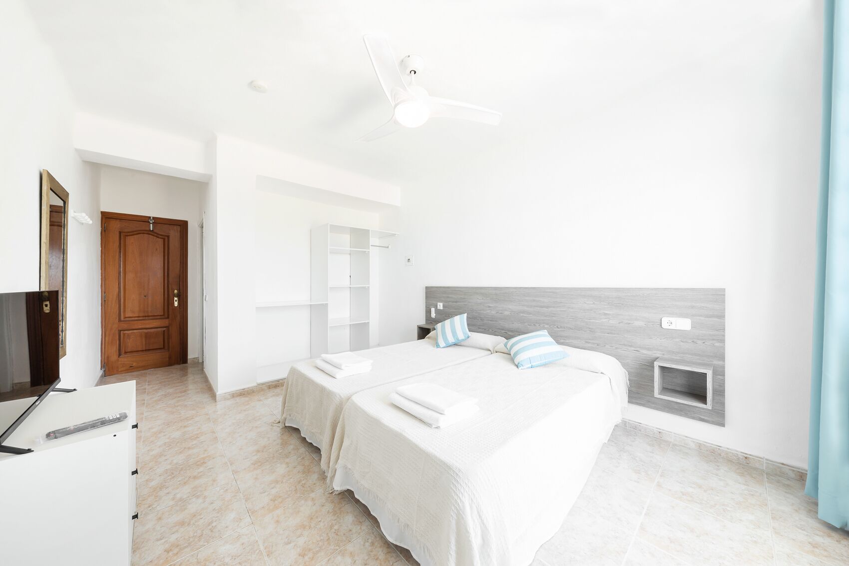 Un dormitorio moderno con cama, armario, escritorio y ventilador de techo.