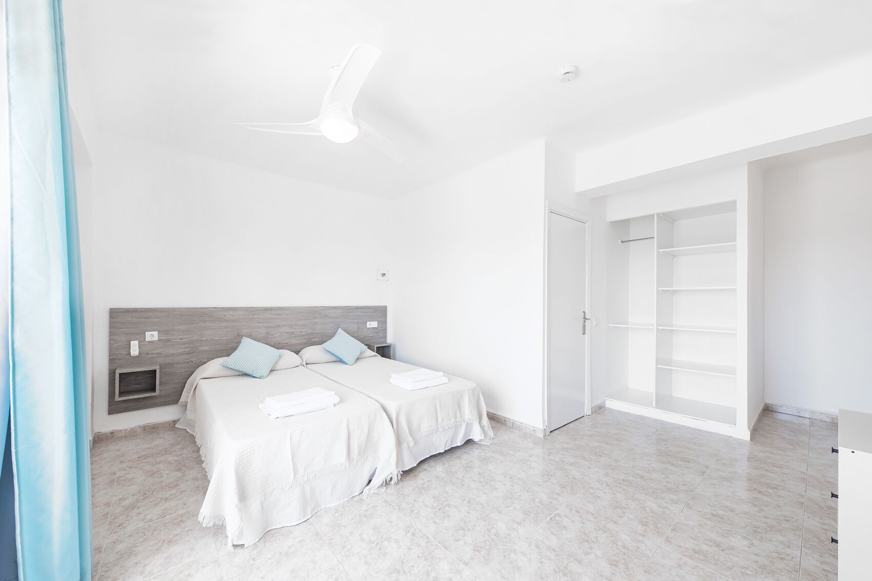 A modern bedroom with a large bed, a wardrobe, and a ceiling fan.