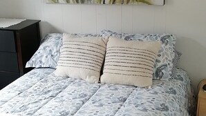 Una cama con un edredón estampado con flores, dos almohadas y un cuadro de flores en la pared.
