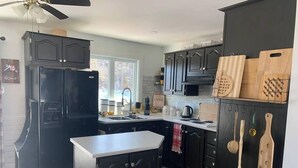 A kitchen with dark cabinets, a refrigerator, a sink, and wooden cutting boards. - Hatchet Harbour Vacation Home (Herring Neck)