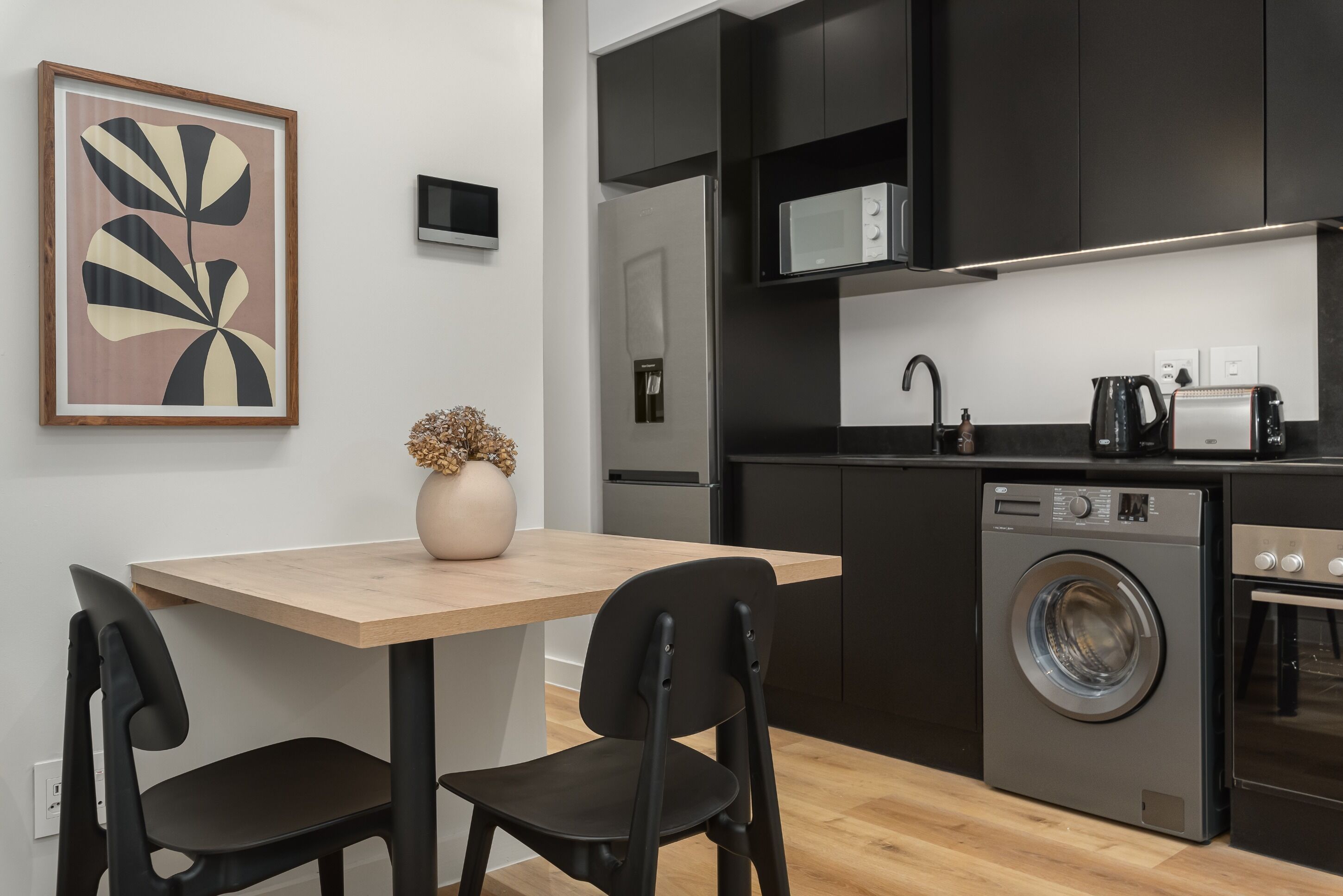 Een moderne keuken met een ingebouwde wasmachine en droger, een magnetron en een koffiezetapparaat.