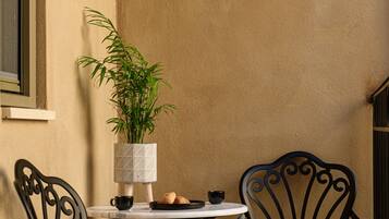 A corner table with two chairs, a potted plant, and a small table with a cup and a pastry.