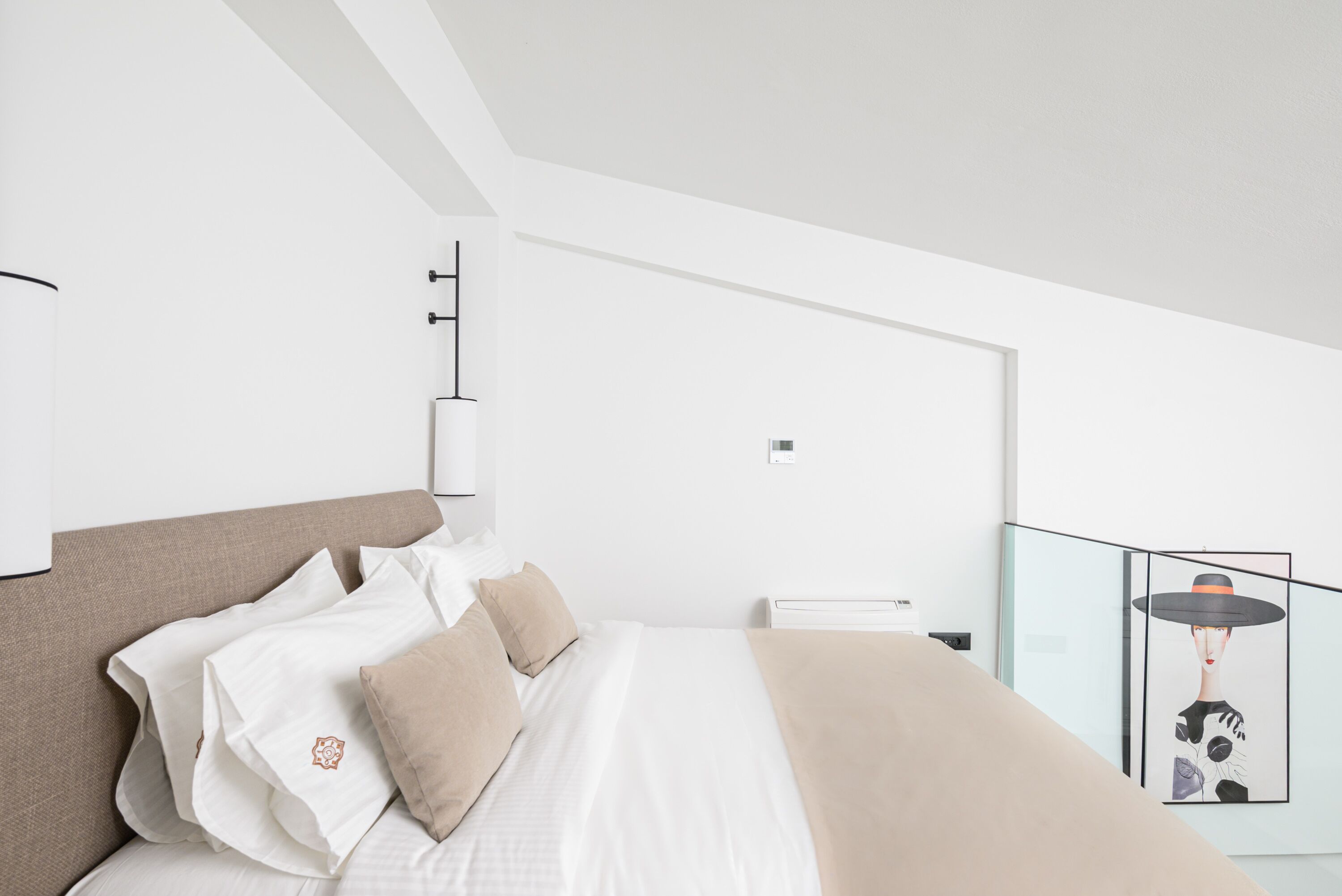 A modern bedroom with a large bed, white bedding, and a minimalist design.