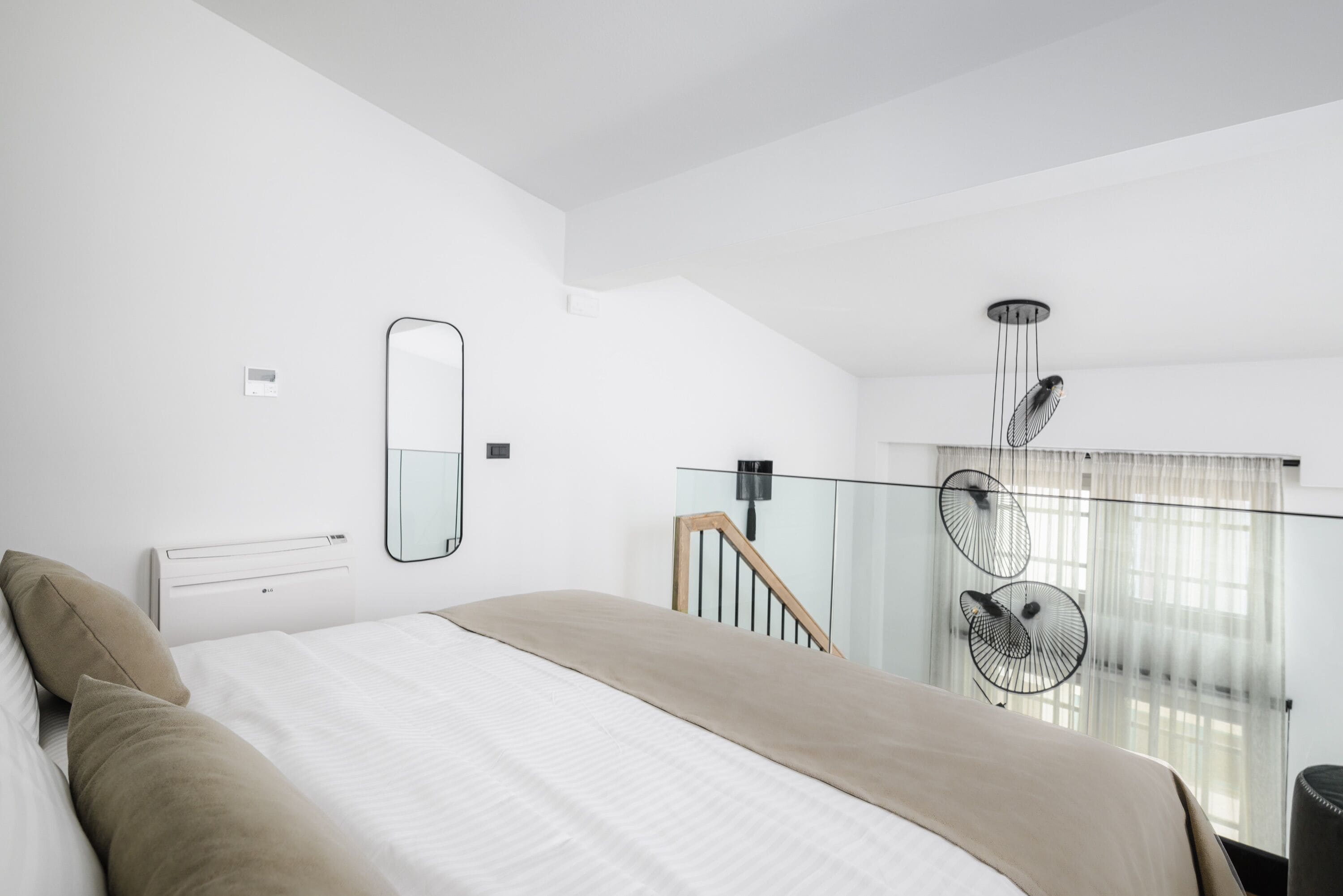 Une chambre moderne avec un grand lit, un miroir, un ventilateur de plafond et une vue sur un balcon.