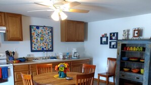 A kitchen with wooden cabinets, a dining table with chairs, a ceiling fan, and a colorful backsplash. - MY HAPPY PLACE - view of Ark from our farm (Williamstown)