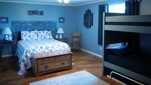 A bedroom with a bunk bed, a wooden nightstand with a lamp, a chair, and a bed with a floral bedspread. - MY HAPPY PLACE - view of Ark from our farm (Williamstown)