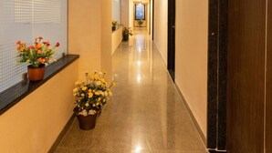 A hotel corridor with a polished floor, a window with a view, and potted plants.