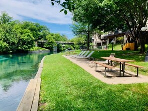A riverside park with picnic tables and lounge chairs.