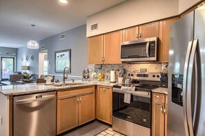 A modern kitchen with wooden cabinets, stainless steel appliances, a built-in microwave, and a dishwasher.