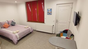 Ein Schlafzimmer mit einem Bett, einem Heizkörper, einer Tür und einem an der Wand befestigten Fernseher.