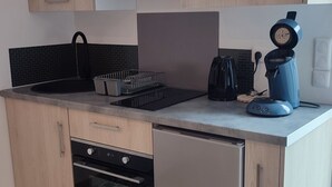 Eine kleine Küche mit Holzausbau, einem Einbauofen, einer Kaffeemaschine und einem Wasserkocher.