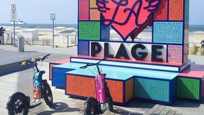 Ein farbiges Schild mit 'CALAIS PLAGE' und einem Herzsymbol, umgeben von Entfernungsangaben zu verschiedenen Städten.