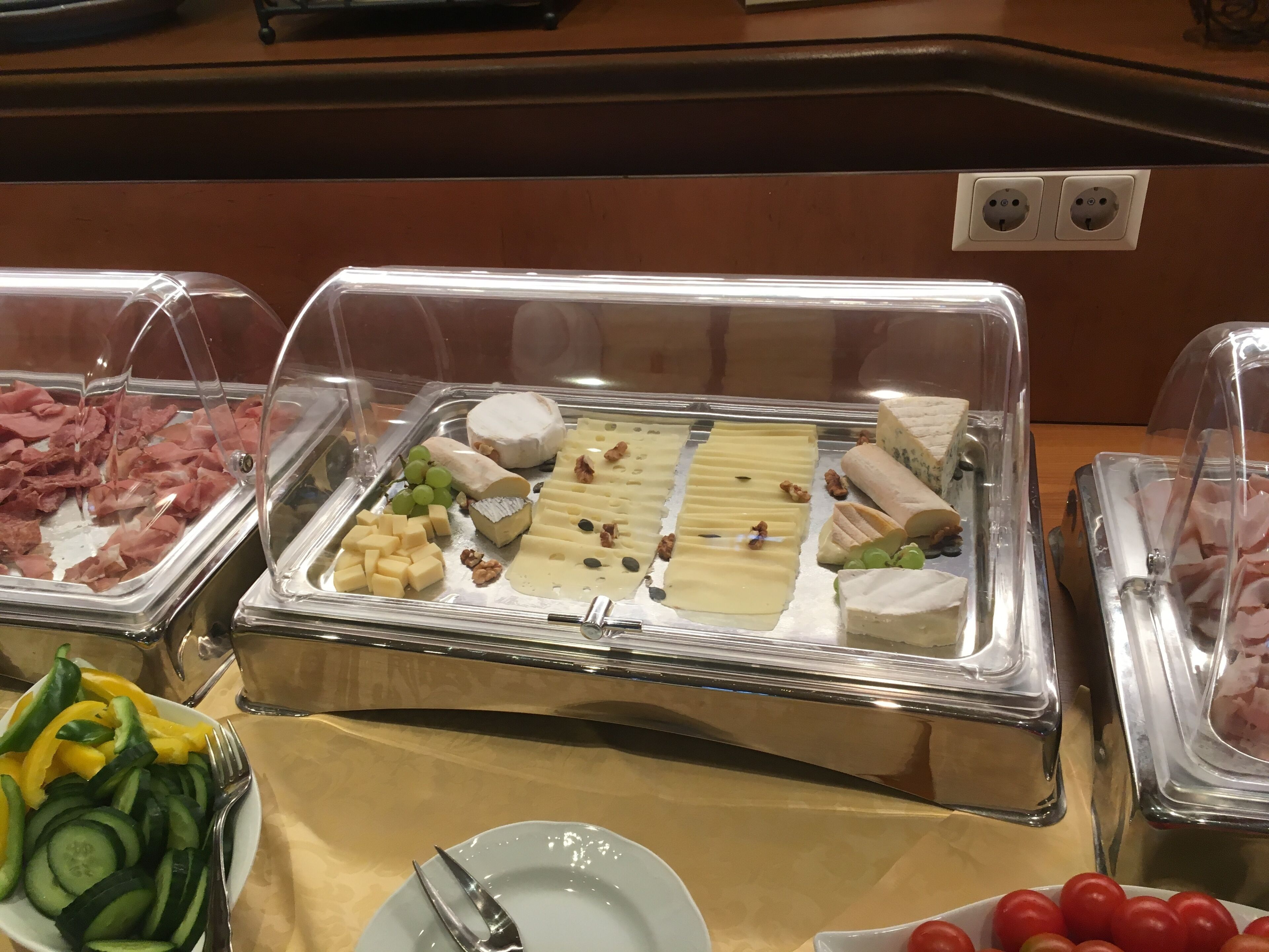 Un bufé con diversos quesos, frutas y verduras.