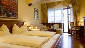 Une chambre d’hôtel avec deux lits, un canapé, un bureau avec une lampe et un tableau au mur.