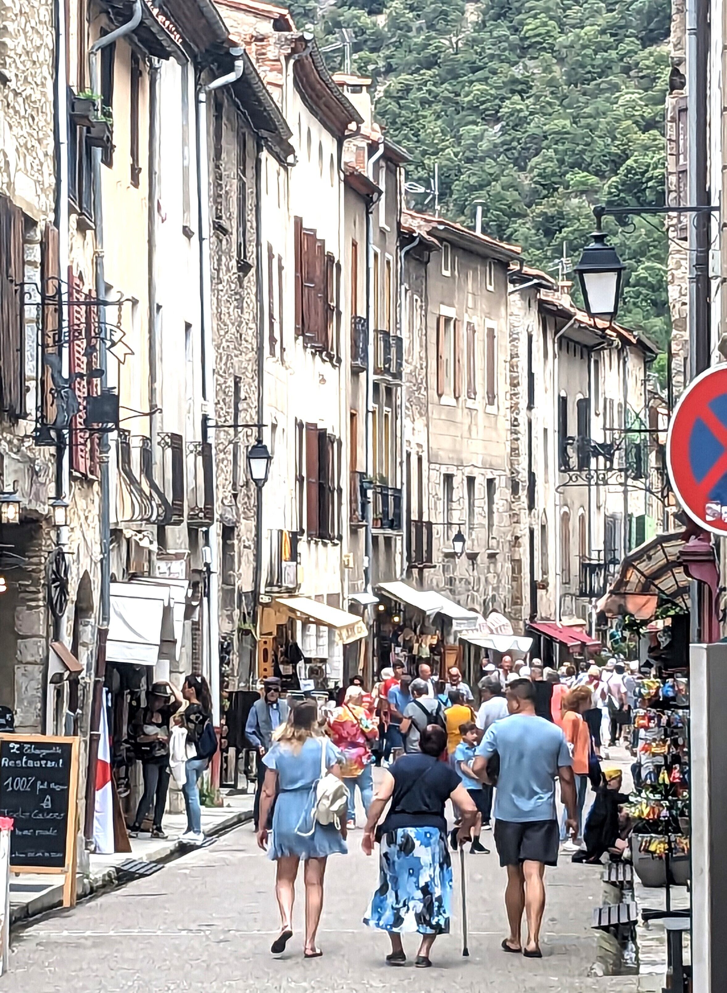 A bustling street with historic buildings, a market stall, and a sign for a restaurant.