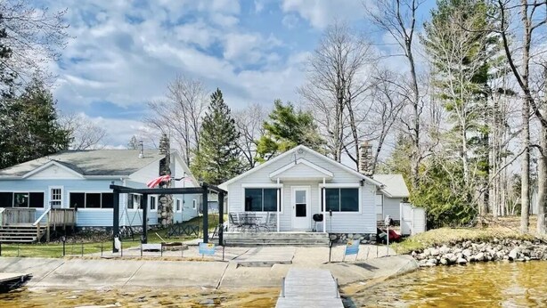 A residential area with a dock leading to a house with a front porch and a garage.