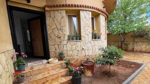 A stone building with a curved entrance, potted plants, and a small garden area.