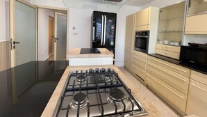 A modern kitchen with a gas stove, oven, refrigerator, and built-in microwave.