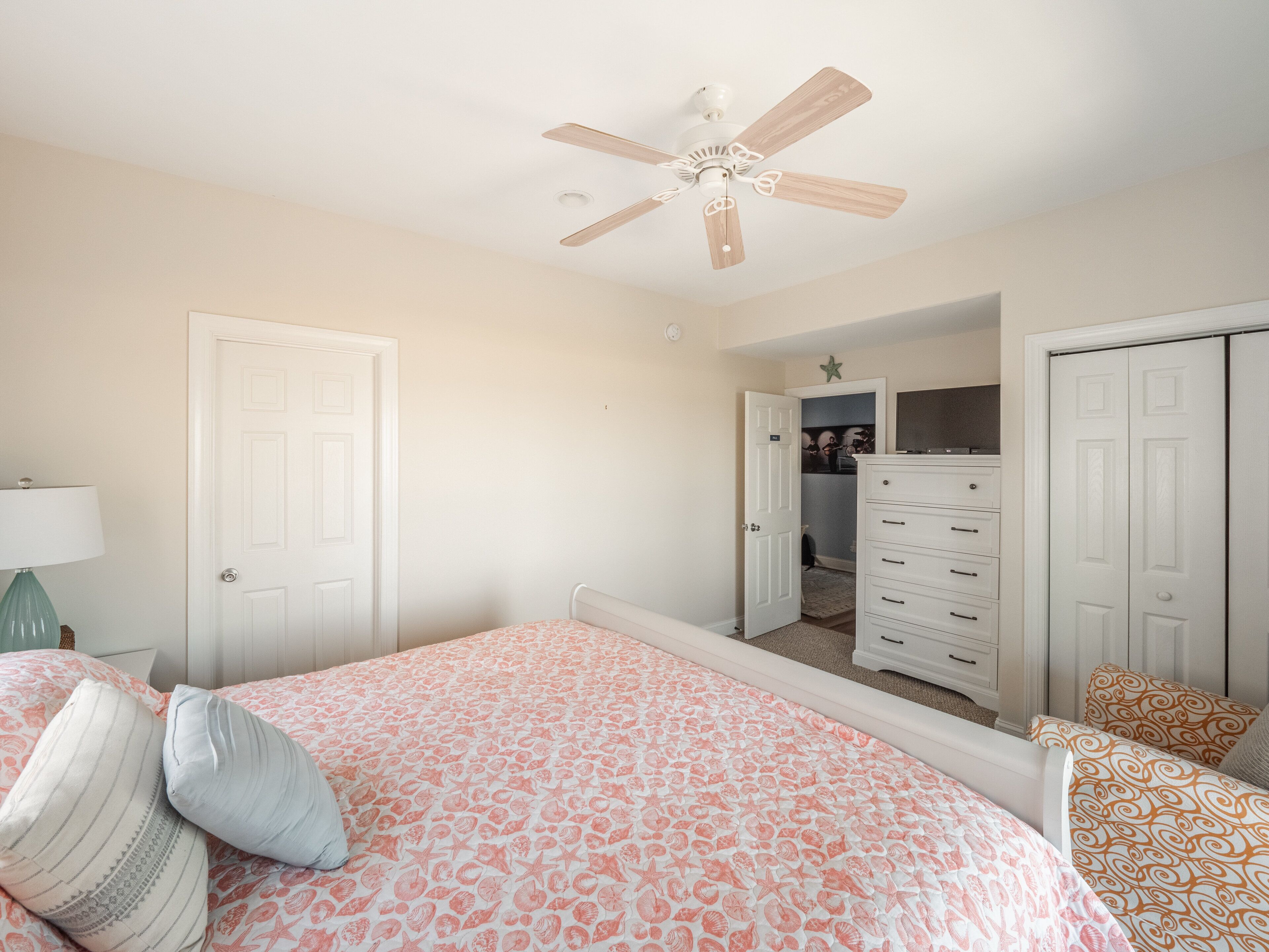 Un dormitorio con cama, cómoda, ventilador de techo y armario.