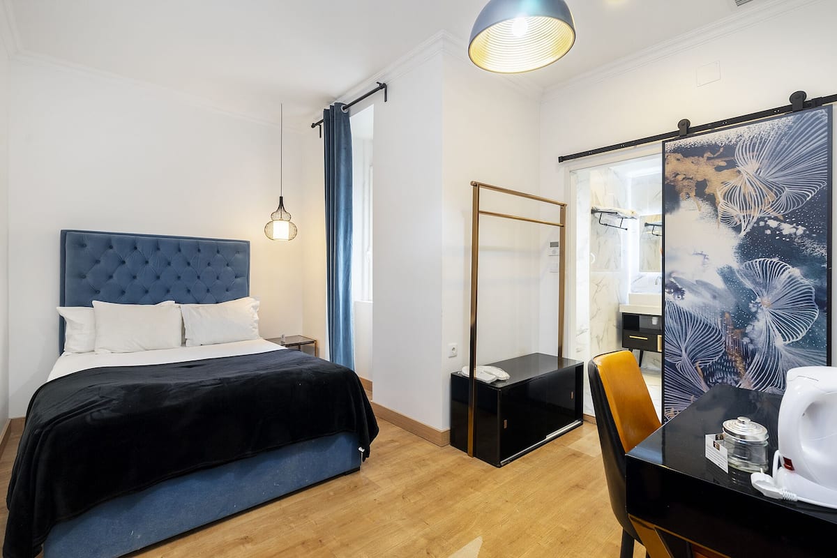 A modern hotel room with a tufted headboard bed, a glass partition, a dining table, and a world map artwork.