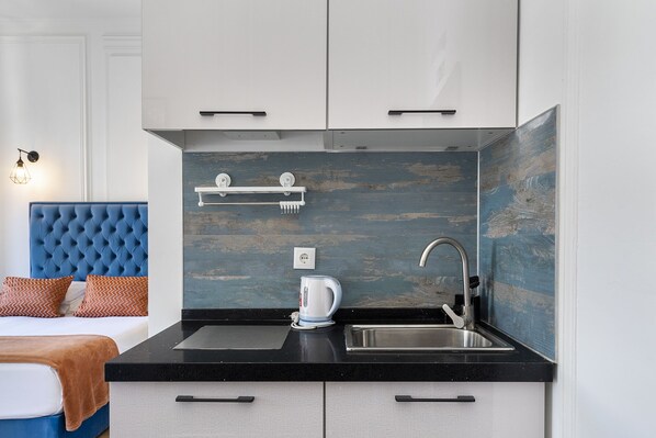 Una cocina moderna con encimera negra, armarios blancos y una pared azul decorativa.