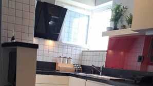 A modern kitchen with white cabinets, a black countertop, and a window providing natural light.