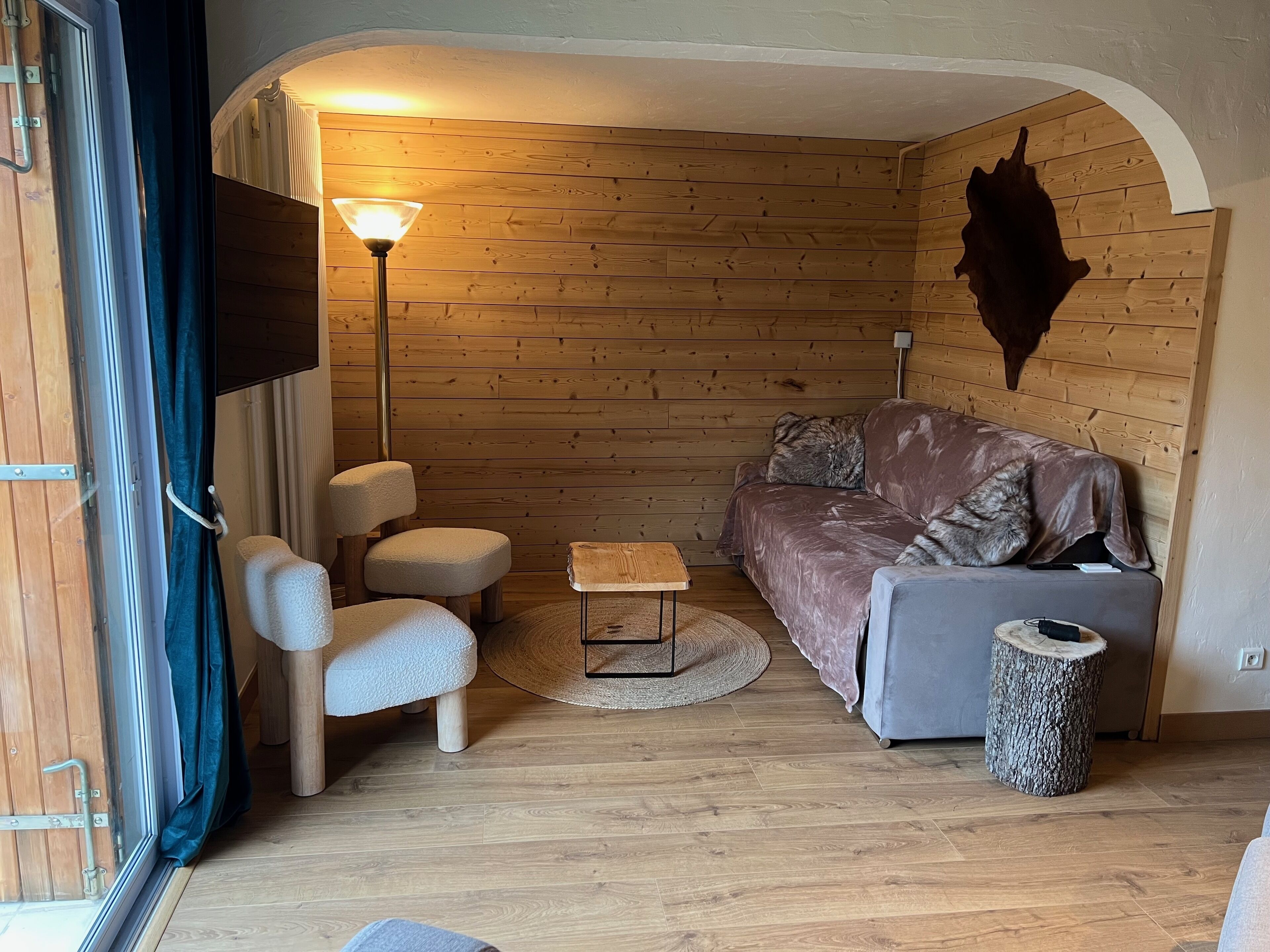 A cozy room with a wooden wall, a sofa, a small table, and a lamp.