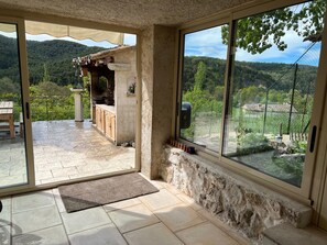 Un ampio patio con pavimento in pietra, una panca di legno e vista su un paesaggio montuoso attraverso ampie finestre.
