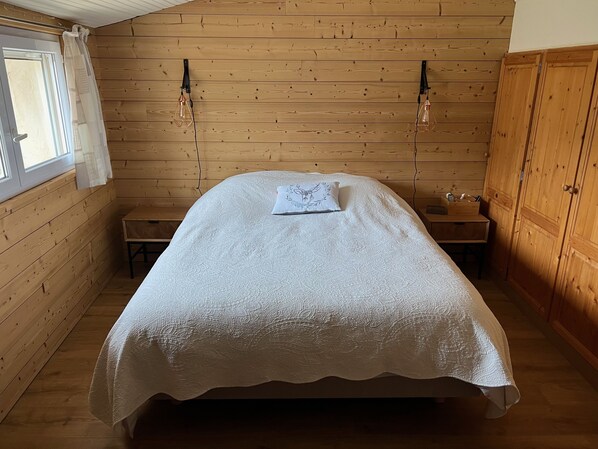Una camera accogliente con travi in legno a vista, un letto singolo con copriletto decorato, un comodino e una piccola scrivania.