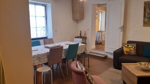 A dining area with a table and chairs, a sofa, and a small table with a bowl. - Gîte Familial « Le Rivallier » Près des Bords de Lallier (Joze)