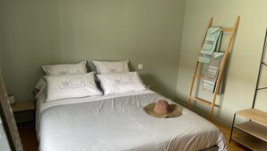 A neatly made bed with white linens and a hat on the bed. There is a wooden ladder against the wall and a shelf with towels. - Gîte Familial « Le Rivallier » Près des Bords de Lallier (Joze)