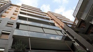 Un moderno edificio de gran altura con varios balcones y ventanas amplias.