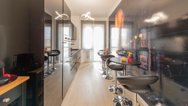 Una cocina moderna con una isla central, taburetes de bar y vistas de la ciudad a través de un ventanal.
