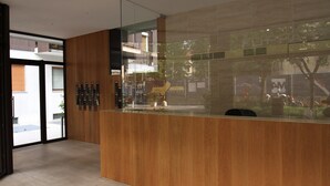 Zona de recepción con mostrador de madera, separador de vidrio y vista a la calle.
