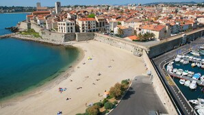 Eine Küstenstadt mit Sandstrand, einer befestigten Mauer und einem Hafen mit Booten.