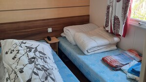Una stanza piccola e accogliente con due letti, una testiera in legno e una finestra con tende decorate.