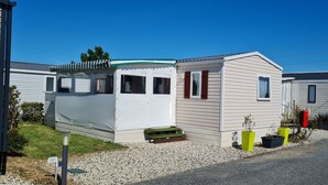 Una casa mobile a un piano con veranda coperta, un piccolo giardino anteriore con ghiaia e una cassetta postale.