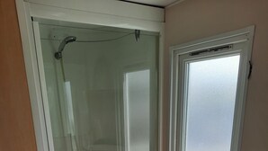 Un bagno con doccia vetrata, lavandino e finestra.