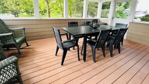 Un patio techado con una mesa y sillas, ventanas amplias y un ventilador de techo.