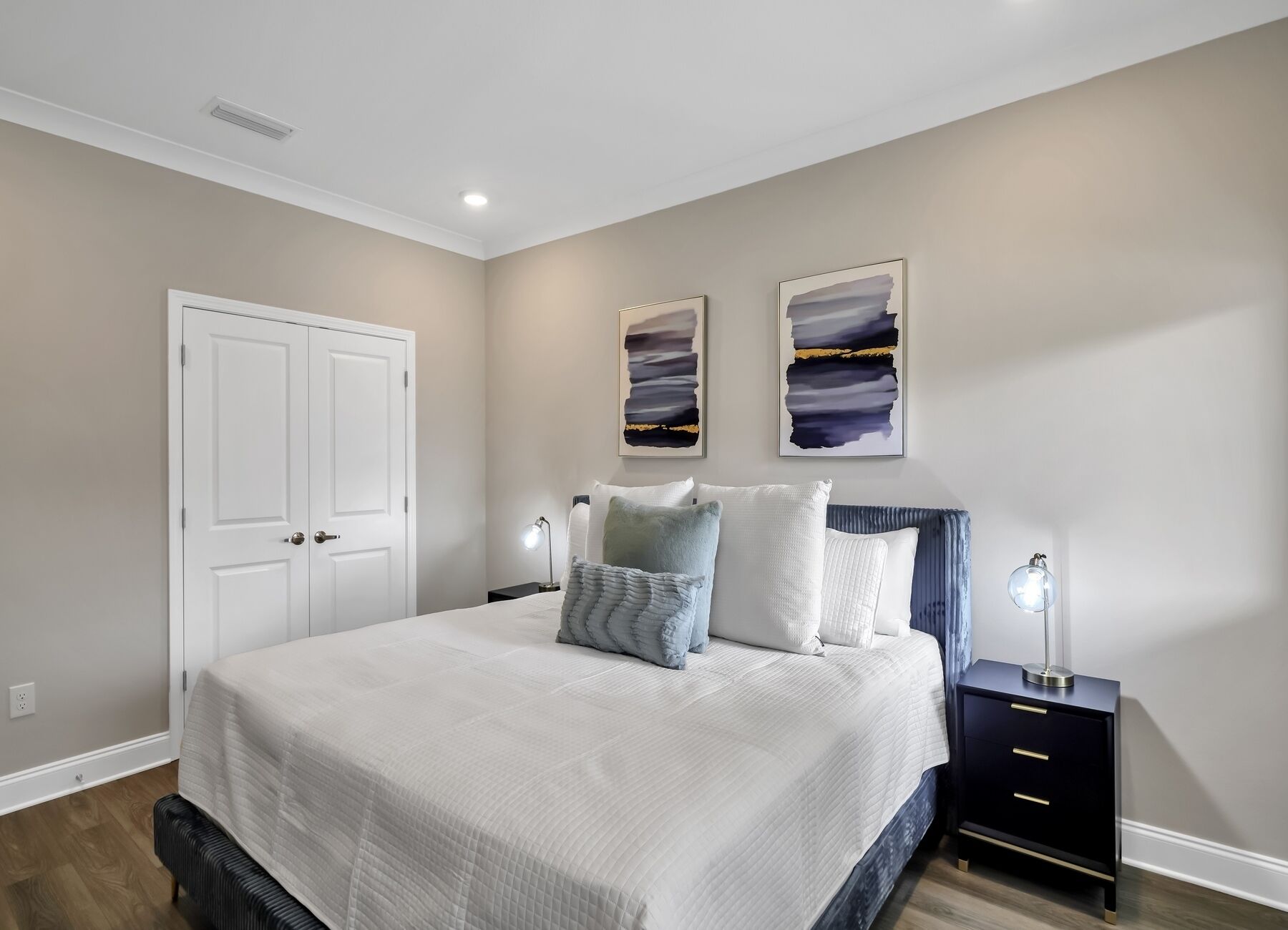 A bedroom with a bed, bedside tables, and artwork on the wall.