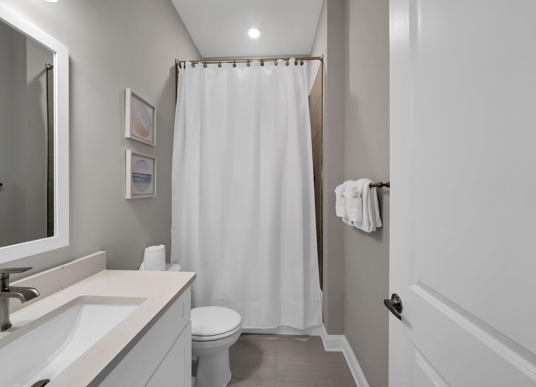 A bathroom with a white sink, toilet, and shower curtain.