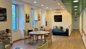A spacious room with a wooden floor, a round table with chairs, a sofa, and a bookshelf. - CiaoMi - Hostel & Long Stay - Milano Niguarda & Bicocca  (Milan)