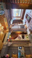 Um átrio em vários níveis com trabalhos em azulejos elaborados e uma escadaria central.