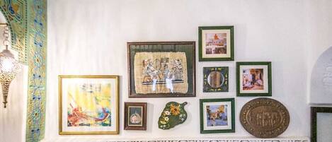 A wall with various framed artworks and a decorative tile border.