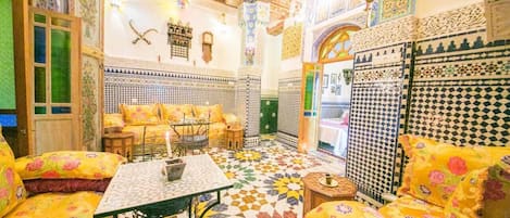 A room with a patterned floor, a sofa set, a table, and a decorative wall.