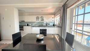 Una cocina moderna con armarios blancos, encimera negra y una mesa con un tazón.